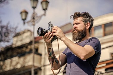 Elle ayarlar. Fotoğrafçı klasik fotoğraf makinesini tutar. Modern blogcu. İçerik yaratan. Sakallı hippi fotoğrafçı. Sakallı ve bıyıklı bir fotoğrafçı. Uzun sakallı bir adam fotoğraf çekiyor.