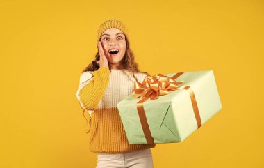 İyi tatiller. Xmas hediye alışverişi. Hediye paketi. Tatlı rüyalar. Boks günü. Genç kız hediye kutusunu tutuyor. Çocuk hediye kutusunu sarı arka planda tut. Satın alma ve teslimat. Alışveriş merkezi. Doğum günü kızı.