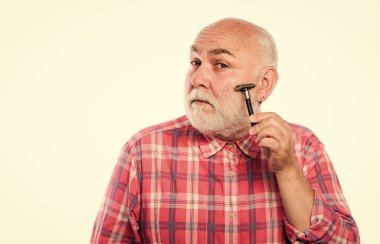 Havalı ve modaya uygun. Tıraşsız yaşlı adamın bıyığı ve sakalı var. Beyaz sakallı, olgun bir adam. Kes ve saç fırçala. Tıraş bıçağı alet çantası. Berber dükkanı konsepti. Traş aksesuarları. Boşluğu kopyala