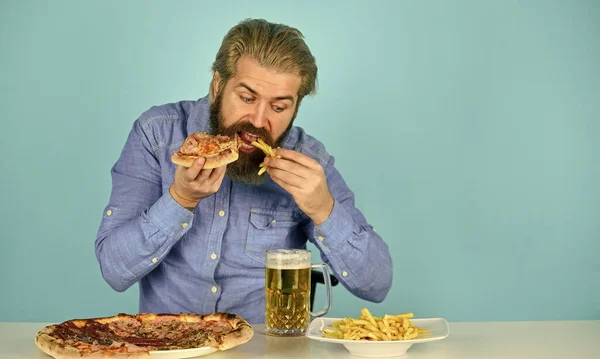 Still hungry. Beer and food. Dinner at pub. Hungry man going to eat pizza french fries and drink beer. Pizzeria restaurant. Cheerful man bearded hipster eat pizza. Pizza party concept. Good appetite — Stock Photo, Image