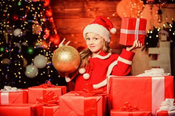 Het kind draagt een kerstmuts met een gewikkelde kerstdoos. De Kerstman bracht me cadeaus. Geluk en vreugde. Kind blij opgewonden meisje vinden geschenken in de buurt van kerstboom. Vrolijk kerstfeest. Gelukkige jeugd concept — Stockfoto