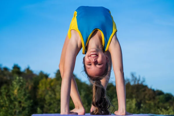 Feliz y deportivo. chica adolescente feliz en el pie de mano. niño tiene cuerpo flexible. niño en entrenamiento de ropa deportiva. concepto de estiramiento y calentamiento. felicidad infantil. salud y estado físico. gimnasia — Foto de Stock