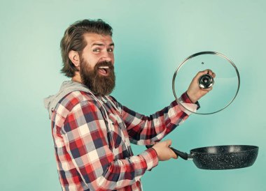 Deneyelim. Tencereli adam. Adam yeni marka tavayı tutuyor. Mutfak gereçleri. Mutfaktaki aşçıda tencereyi pişirirken. Yemek hazırlamak ve yemek pişirmek. Mutfak aletleri. Mutfak reklamları