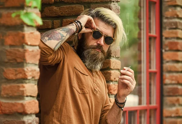 Man Smoking Outdoor. Fashionable mature man smoking cigarette. Punk hipster man smoking. Smoking and habit. secondhand or passive smoke. brutal caucasian male in glasses