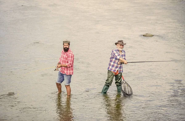 Allt är möjligt. Landsbygdsflykt. hobby. Vild natur. Camping på stranden av sjön. far och son fiskar. Tjuvjakt. två glada fiskare med fiskespö och nät. Storviltsfiske. vänskap — Stockfoto