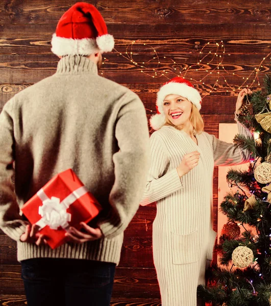 Surprising his wife. Giving and sharing. Generosity and kindness. Prepare surprise for darling. Winter surprise. Man carry gift box behind back. Woman smiling face santa. Christmas surprise concept