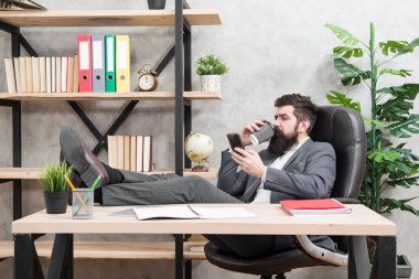 Kahve başarılı müzakerelerin teminatıdır. Kafein bağımlısı. Cep telefonu. Güne kahveyle başla. Kahve molası. Patron enerji içeceğini seviyor. Sakallı iş adamı elinde bardak ve akıllı telefon tutuyor.