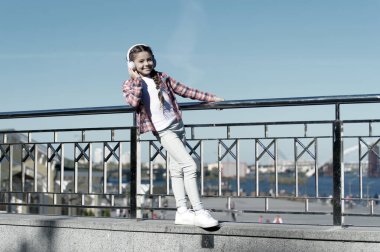 Çocuğunuzu en iyi çocuk kulaklıklarıyla mutlu edin. Her yerde müziğin tadını çıkar. Dinlemeyi hak eden en iyi müzik uygulamaları. Kız çocuk açık havada modern kulaklıklarla müzik dinliyor.