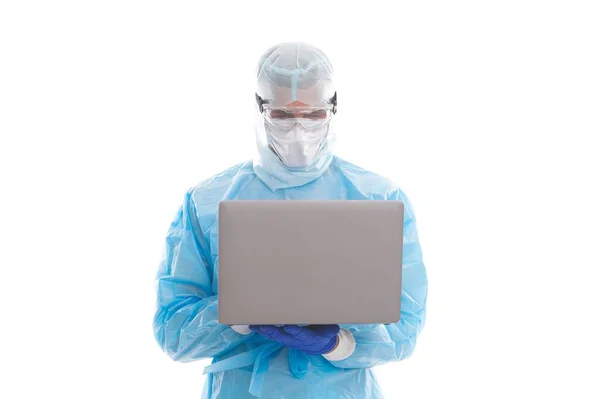 Врач-эпидемиолог в маске респиратора и защитном костюме во время пандемии коронавируса, работающий на компьютере, онлайн-помощь. — стоковое фото