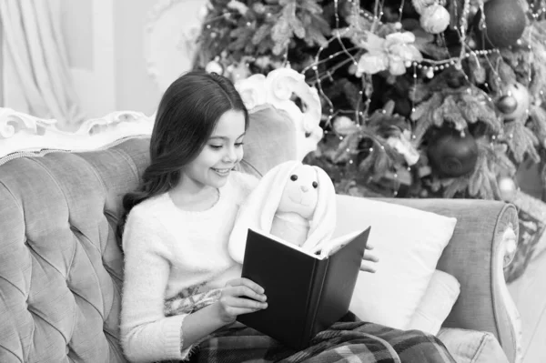 Reading is always a good idea. Little girl read book to toy friend. Small child enjoy reading xmas story. Winter reading at Christmas tree. Holiday reading list