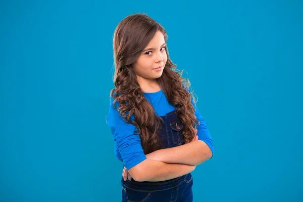 Criança segura as mãos confiantemente cruzou o peito. Psicologia e desenvolvimento infantil. Postura confiante. A criar confiança. Miúda menina cabelo longo posando com confiança. Menina penteado encaracolado se sente confiante — Fotografia de Stock