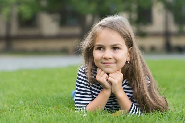 Glad liten unge leende med friska ansikte hud och långt hår ligger på grönt gräs naturliga sommarlandskap, hudvård — Stockfoto