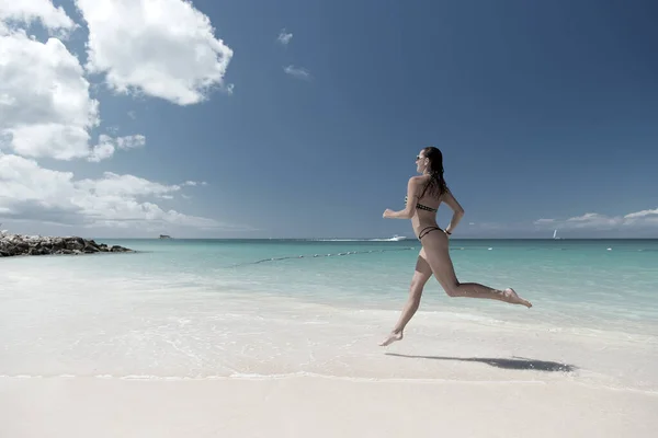 Girl with sexy body in swimsuit running on sea beach — Stock Photo, Image