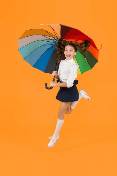 Een energieke blik. Schattig meisje springen met herfst look op gele achtergrond. Schattig schoolkind met glamour look met kleurrijke paraplu. Schooluitstraling van klein kind — Stockfoto