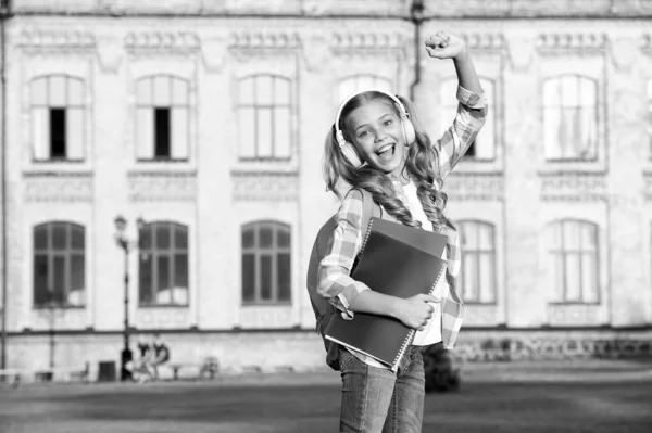 Bambina con libro e auricolare. letteratura per bambini. sviluppo dell'infanzia. lavorare con il notebook. Torniamo a scuola. studio dei bambini nel parco. rilassarsi su erba verde con libro. ascoltare musica online — Foto Stock