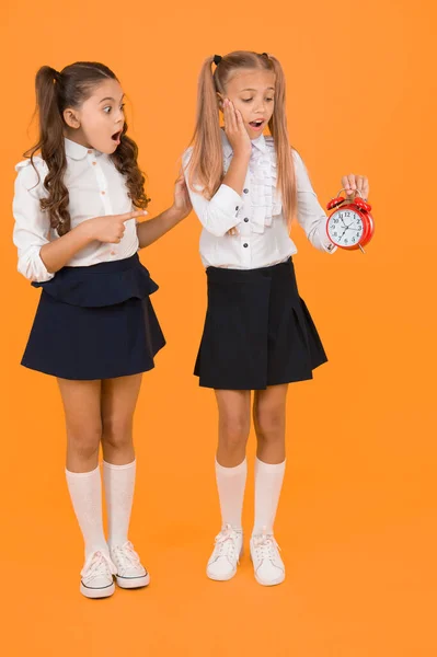 Tijd voor pauze en ontspanning. Het alarm gaat af. Tijd voor de lunch. Schoolrooster. Schoolmeisjes en wekker. Kinderen scholieren schattig formeel uniform outfit. Kinderen houden wekker tellen tijd — Stockfoto