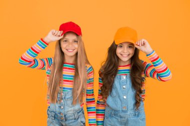 Hippi alt kültürü. Sarı arka planda beyzbol şapkası takan küçük mutlu hippiler. Modaya uygun bir şekilde gülümseyen sevimli hippiler. Hipster tarzı sevimli çocuklar.