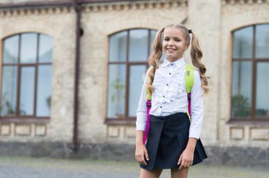 Uzun kuyruklu mutlu çocuk 1 Eylül 'de okul bahçesinde moda üniforması giyerek okula geri dönüyor.