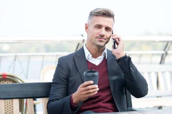 Hablando de negocios con una taza de café. Un hombre guapo tiene conversación telefónica. Comunicación empresarial. Conversación móvil. Descanso. La vida moderna. Nuevas tecnologías — Foto de Stock