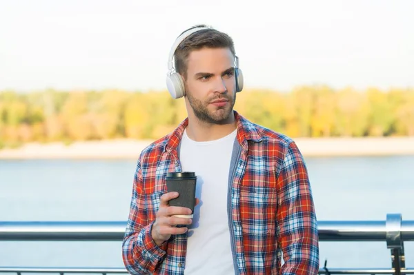 Ώρα για διάλειμμα. Ο άνθρωπος με τα ακουστικά ακούει το τραγούδι. στυλ μουσικής. μαθαίνοντας πίνοντας καφέ. ποιότητα του ήχου. Καλημέρα ποτό. αξύριστος τύπος με φλιτζάνι καφέ. αρσενικό casual μόδα hipster — Φωτογραφία Αρχείου
