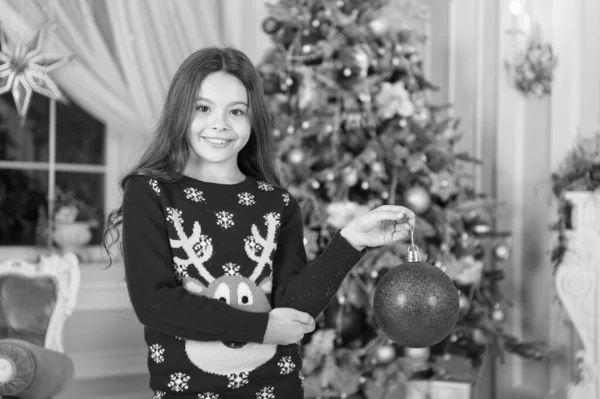 El rojo es mi favorito. Decoración de atributos navideños. Niña cerca del árbol de Navidad. El niño celebra la Navidad en casa. Tradiciones invernales. Concepto de tienda de regalos. Adorable niño emocionado usar suéter de Navidad — Foto de Stock