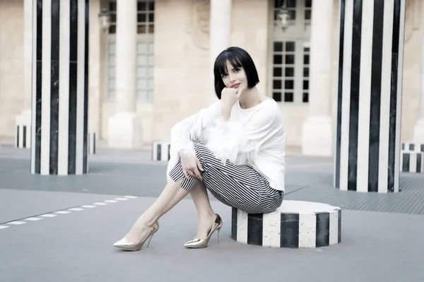 Concepto de moda urbana. Chica de moda dama con peinado bob al aire libre de la arquitectura urbana de fondo. Mujer modelo de moda posando al aire libre. Chica morena bob peinado se ve elegante — Foto de Stock