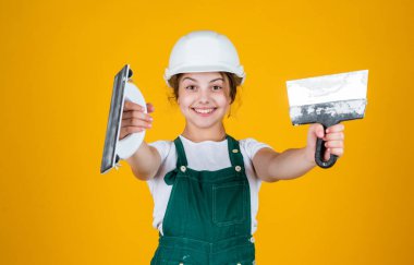 Sanırım sana yardım edebilirim. Kasklı çocuk inşaat alanında. Alet spatulası olan genç bir sıva ustası. Çocuk tamir işiyle uğraşıyor. Atölyede yenileme konsepti. Meşgul profesyonel marangoz malayla