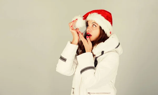 Ожидание морозных рождественских дней. Эмоциональное женское гримерное лицо. Девчонка. Девушка в белой куртке и шляпе Санты. Куртка имеет дополнительную изоляцию, чтобы защитить ваше тело от резкой зимней погоды. Белая куртка — стоковое фото