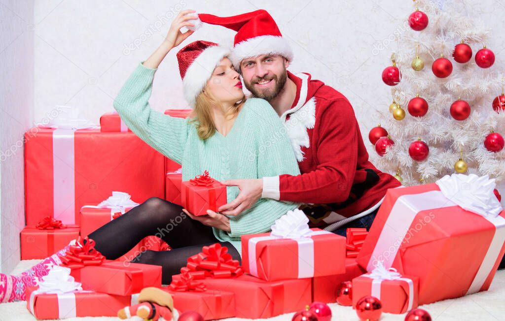 Couple in love enjoy christmas holiday celebration. Opening christmas present. Pleasant surprise. Couple sit near pile of gift boxes and christmas tree background. Husband prepared christmas surprise