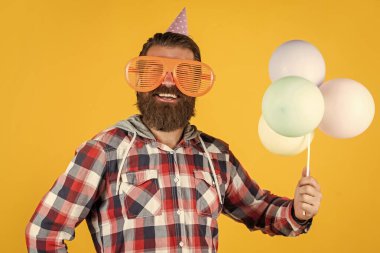 Bu da senin için. Mutlu bir partiyi kutluyoruz. Parti elemanları ve tatil eşyaları. Çok renkli eğlence. Emeklilik için en iyi parti. Sakallı ve bıyıklı neşeli bir adam. Balonla gülümseyen hippi