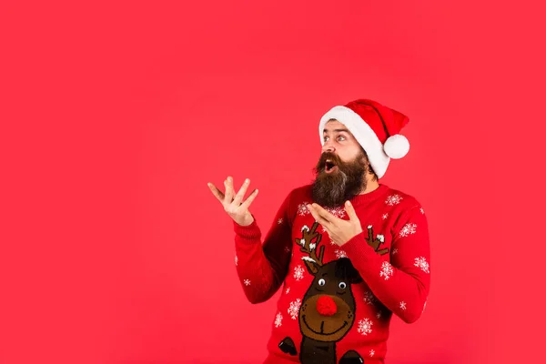 Promoting goods. Santa man. New year party. Christmas time. Have fun. Finding perfect present. Bearded man santa hat. Emotional hipster winter knitted sweater red background. Winter holiday fun — Stock Photo, Image