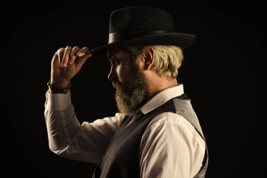 Geçmiş yüzyıllar trendi. Retro beyler. Olgun yakışıklı adam. Klasik şapka görünümlü bir adam. Zalim sakallı hippi. Gerçek erkeklik. Erkeksi görünüş. Sakallı adam siyah arka plan. Sakal bakımı.