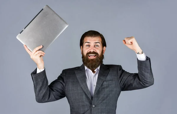 Celebrando el éxito. empleado masculino que sostiene informe financiero e investiga en el espacio de coworking en el ordenador portátil. nueva tecnología en los negocios modernos mentira. feliz caucásico barbudo hipster con ordenador —  Fotos de Stock