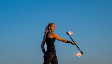 Tehlikeyle flört ediyor. Seksi ateş sanatçısı mavi gökyüzü. Şehvetli kadın alevli çubuğu manipüle ediyor. Yangın gösterisi. Sopa çevirme. Gece partisi. Tatil kutlaması. Gösteri gerçekten çok ateşli.