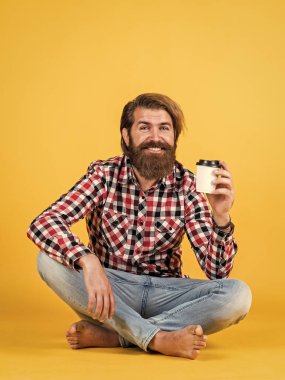 Keyfi yerinde. Mutlu sakallı adam sabah kahvesini içiyor. Adam kağıt bardaktan sıcak çay içiyor. Günaydın. Enerjik, sıcak içecek. İlham almak için kahve lazım.