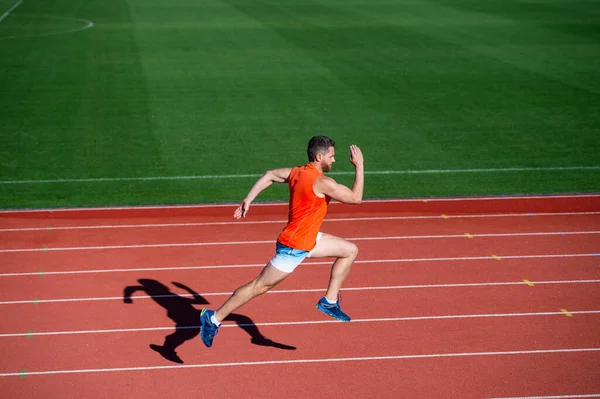 Atlético muscular homem correndo em pista de corridas no estádio ao ar livre, acabamento — Fotografia de Stock