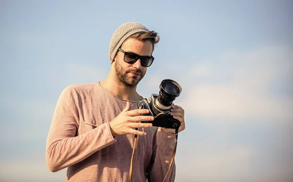 Hipster reporter taking photo. Guy photographer outdoors sky background. Handsome photographer guy retro camera. Manual settings. Photojournalist concept. Travel blogger. Professional photographer — Stock Photo, Image