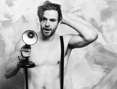 Pantolon giymiş, elinde lamba tutan beyaz sakallı, maço bir adam.