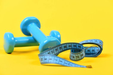Şekil verme ve fitness ekipmanları. Bant rulosunun yanındaki halterler