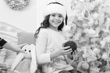 Noel 'i eğlenerek kutlayın. Mutlu çocuk Noel 'i ve yeni yılı kutluyor. Noel Baba bakışlı küçük kız. Noel ağacı süslüyorum. Mutlu noeller. Mutlu yıllar.