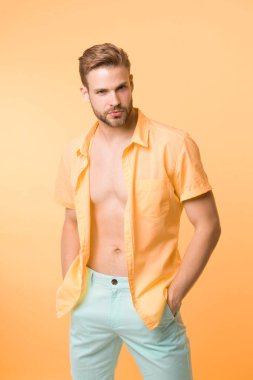 Seksi gövde görmek ister misin? Burası çok sıcak. Sana seksi vücudumu göstereceğim. Yakışıklı, sakallı, sarı arka plan elbiseli adam. Kendine güvenen çekici maço gömleğinin düğmelerini açarken kendini seksi hissediyor.