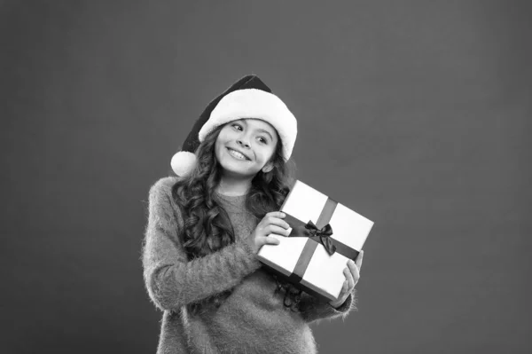 クリスマスプレゼント。女の子プレゼントボックス。お正月のお祝い。クリスマス・ホリデー・パーティー。サンタ・ハットの少女。明るい赤い壁。子供の買い物売り上げ。クリスマスボクシングの日だ。最高のクリスマスオファー — ストック写真