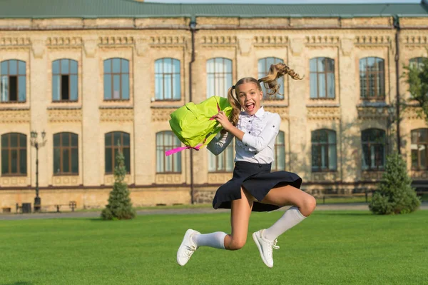 Happy energetic child in formal uniform hold school bag jumping in schoyard, schooling – stockfoto