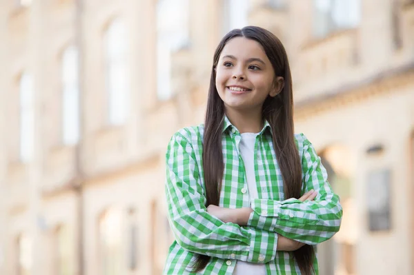 Confident happy girl with long hair in casual style keep arms crossed urban outdoors, confidence