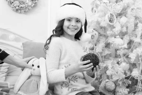 Comemore o Natal com diversão. A criança feliz celebra o Natal e o Ano Novo. Menina com olhar de Papai Noel. A decorar a árvore de Natal. Feliz Natal. Feliz Ano Novo — Fotografia de Stock