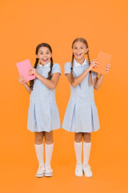 Kitapçı konsepti. Klasik çocuk modası. Okula dönüyorum. Küçük kızlar çalışma kitabını ve not defterini tutarlar. Çocuklar için ansiklopedi kitabı. Küçük kızlar okumayı sever. Eski usul. Eski üniformalı arkadaşlar şaşırdı.