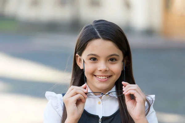 Sorriso bambino felice con sguardo scolastico che tiene gli occhiali all'aperto, occhiali — Foto Stock