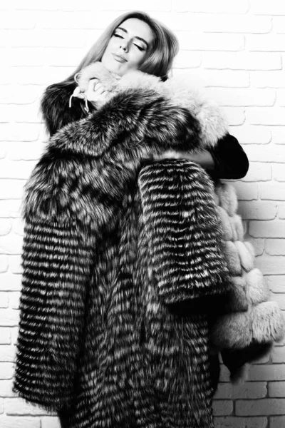 満足したファッショナブルな女性で毛皮の上の白いレンガの壁のスタジオの背景 — ストック写真
