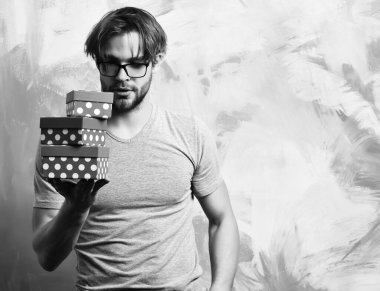 Beyaz sakallı seksi maço adam elinde hediye kutuları tutuyor.