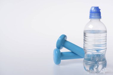 Su şişesinin arkasındaki halterler, kopyalama alanı. Sağlıklı yaşam tarzı ve spor